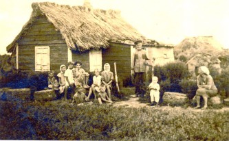 Здесь мне два года. Рядом – прадед, Степан Керсанович, родовой казак. За отказ снять лампасы сидел на Соловках. Умер в 104 года, когда мне было уже 6 лет. Бабушка Ульяна говорила, что я казак 24 золотников. Золотник – это колено. Мы стоим перед летницей. Крыша покрыта чагой. Чага – это пойменный камыш, он растет только в очень чистой воде. Трубчатый, мягкий материал.